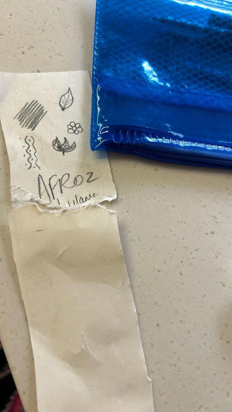A torn strip of paper with doodles and the name AFROZ handwritten in pencil